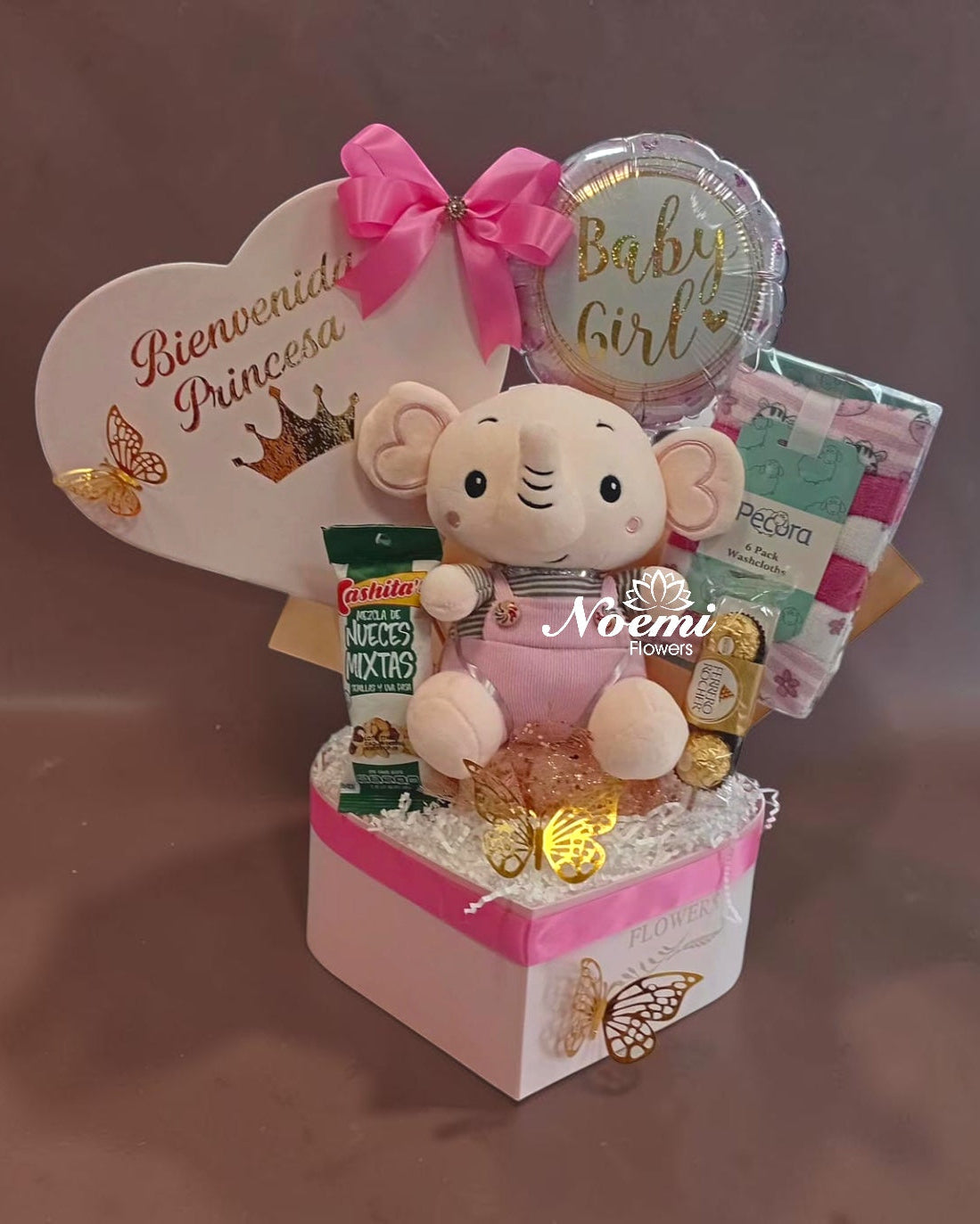 Cajita especial para recibir a la nueva princesa. Incluye peluche elefantita rosa, globo "Baby Girl", tarjeta corazón "Bienvenida Princesa", chocolates Ferrero Rocher, nueces mixtas Kashita's, set de toallitas y mariposas decorativas doradas. Todo presentado en caja rosa con lazo y papel rizado.
