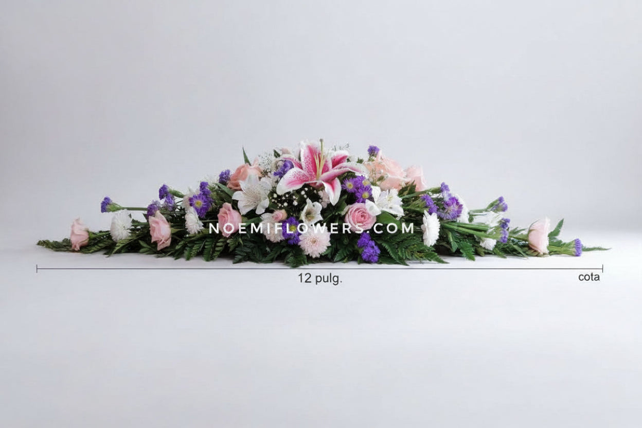 Centro de mesa alargado que combina rosas, lirios, mini rosas y margaritas sobre un elegante follaje variado.- Floristería Noemi Flowers