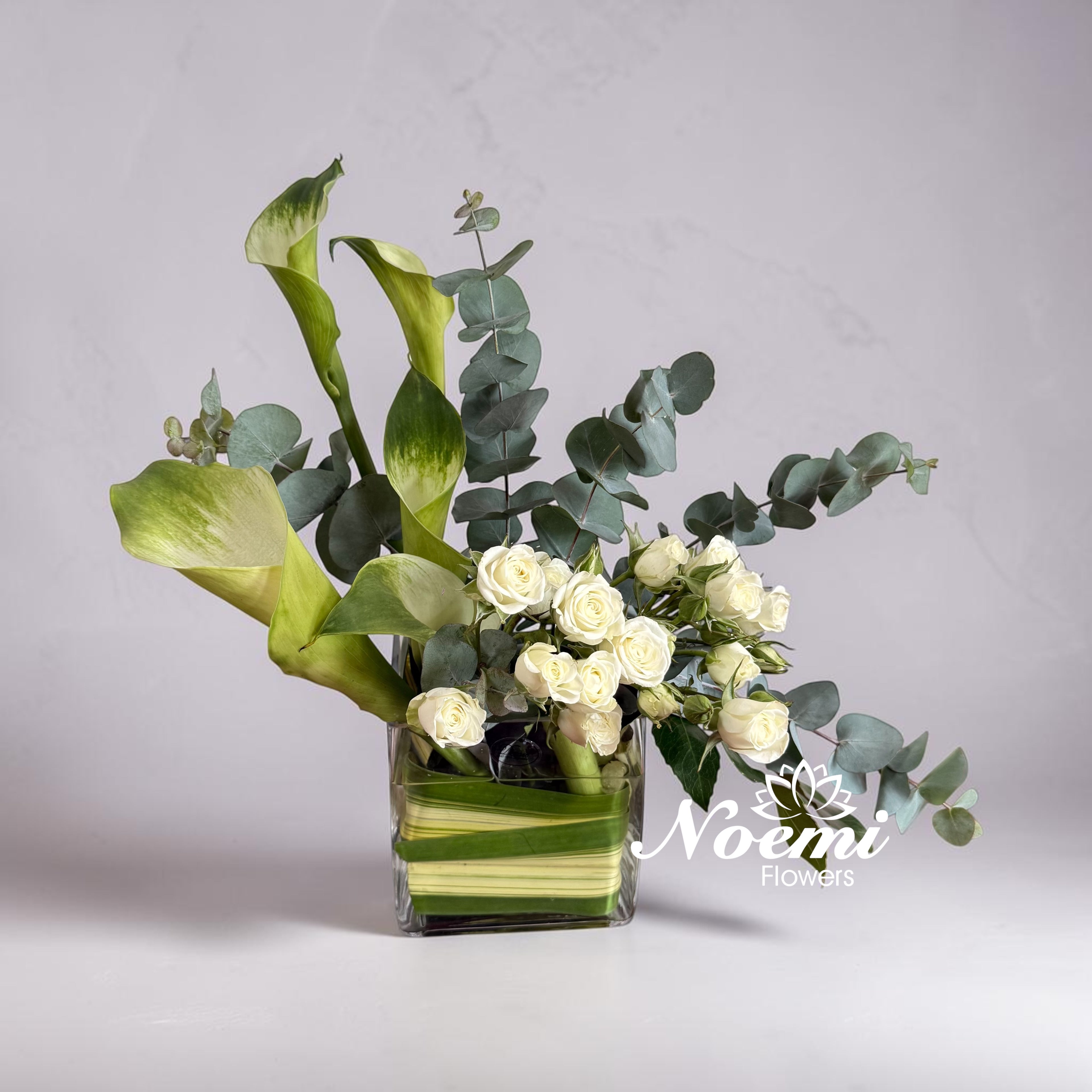 Arreglo floral confeccionado con mini rosas, cala, eucalipto - Floristería Noemi Flowers. 