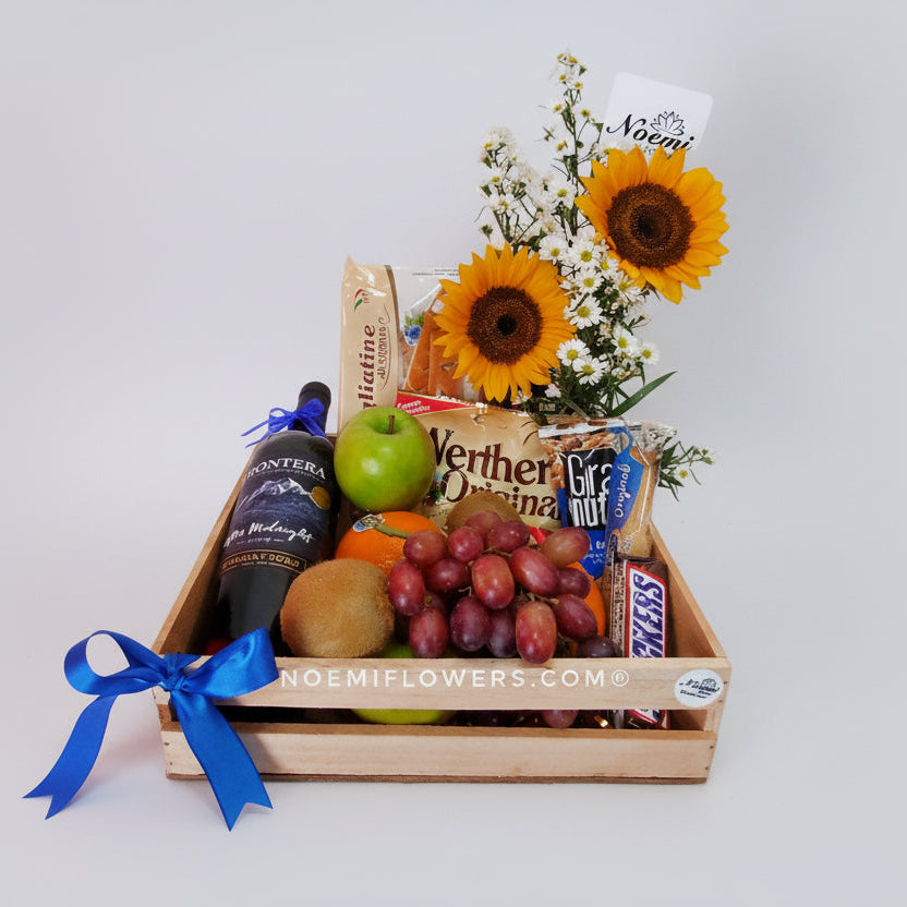 Regalo con frutas vino snacks y girasoles - Floristería Noemi Flowers